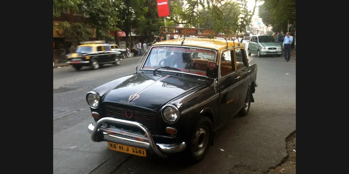 1964 Premier Padmini. Photograph by Ask27, CC BY-SA 3.0. https://commons.wikimedia.org/wiki/File:Premier_Padmini_Taxi_in_Mumbai_2012.JPG Fit to 2:1 with dark side borders.